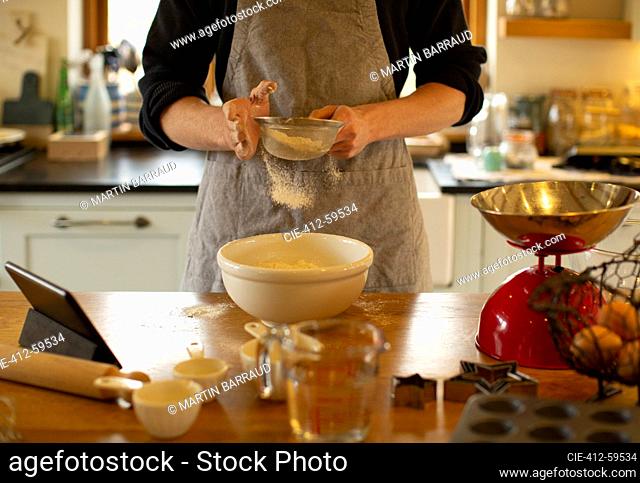 Man baking sifting flour into bowl in kitchen