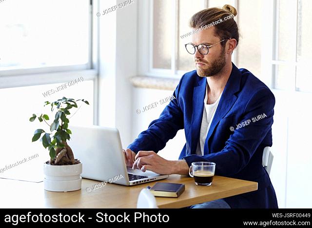 Businessman using laptop at table in modern office
