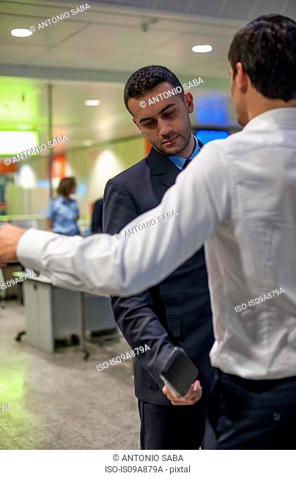 Security guard checking male passenger in airport security
