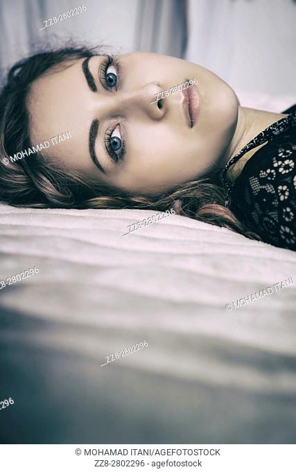 Beautiful young woman laying down in bed