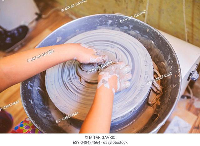 Young artist hands shaping clay on pottery wheel at workshop