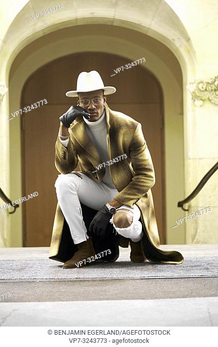 successful wealthy man crouching on floor, confidence, wearing stylish trend outfit, men'S fashion, in city Munich, Germany