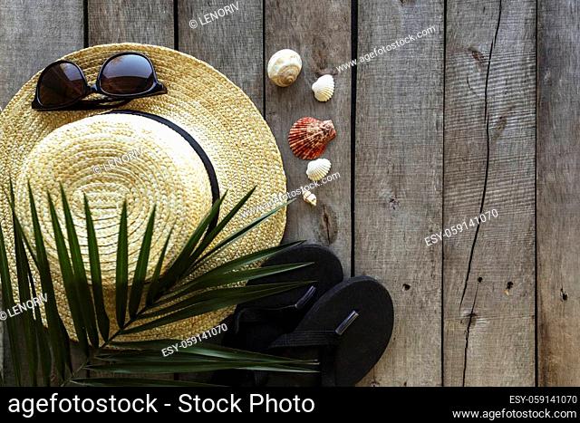 Travel, vacation concept. Straw hat, palm leaf, eyeglasses, sea shells and black shoes on wooden background. Relax. High quality photo