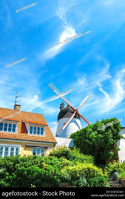Idyllic mill in a small town under a blue sky with a green garden in the front