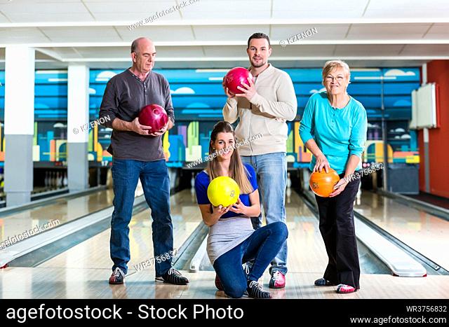 Smiling family holding multi colored bowling ball posing