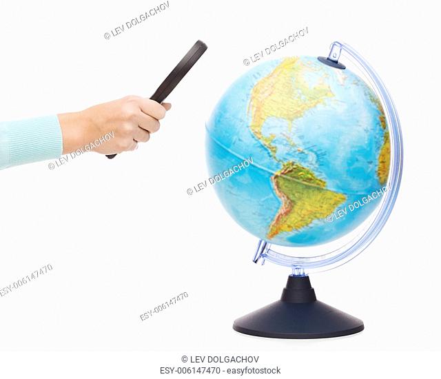 travel, earth, geography and research concept - close up of woman hand holding magnifying glass over earth globe