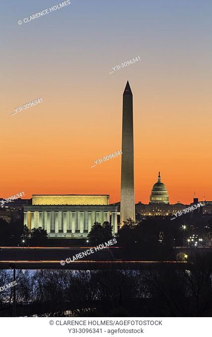 The Lincoln Memorial, Washington Monument, and US Capitol building set against an orange sky during morning twilight in Washington, DC