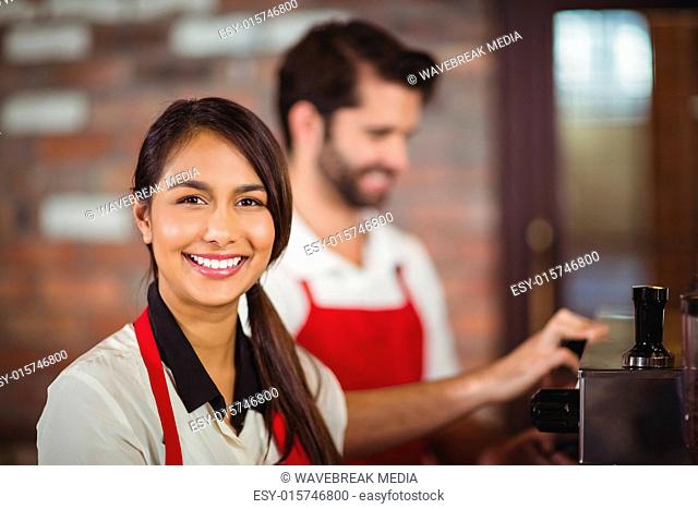 Smiling waitress using the coffee machine