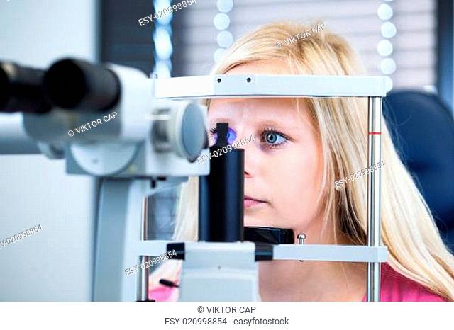 Optometry concept - pretty, young female patient having her eyes examined by an eye doctor