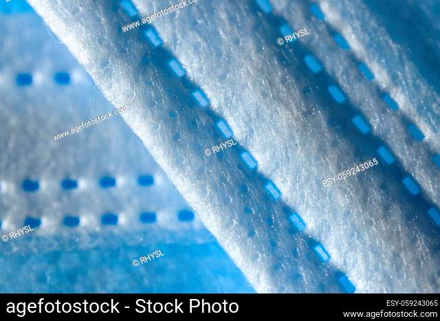 Super macro abstract close up of a 3-ply disposable face mask. Individual fibers visible along the printed paper like seam. Background with copy space