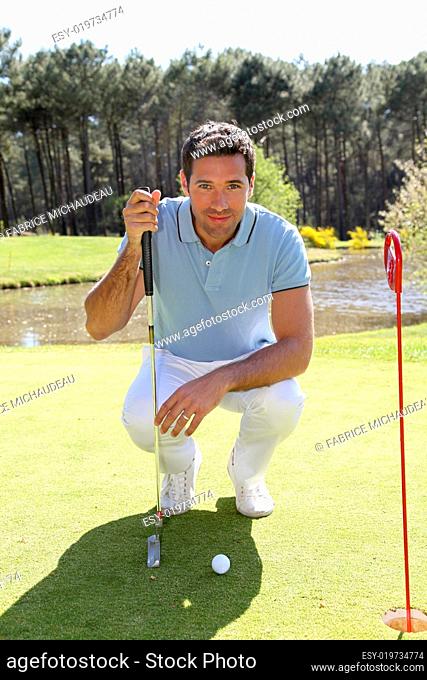 Golfer kneeling in front of golfball