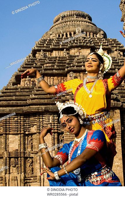 Odissi dancers strike pose re-enacts Indian myths such as Ramayana in front of iconic Sun Chariot in world heritage Sun temple complex in Konarak , Orissa