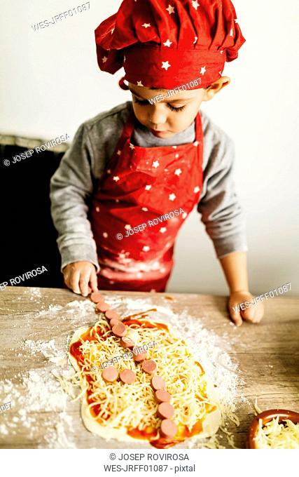 Little boy preparing pizza at home