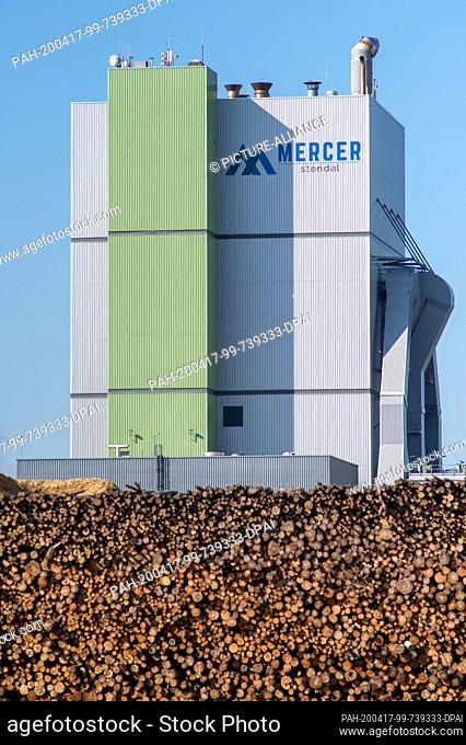 06 April 2020, Saxony-Anhalt, Anrneburg: Industrial plants of the company ""Mercer Stendal"" tower above a pile of tree trunks