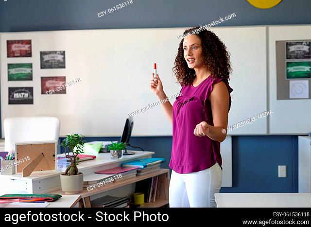 Caucasian young female teacher holding felt tip pen while teaching in class