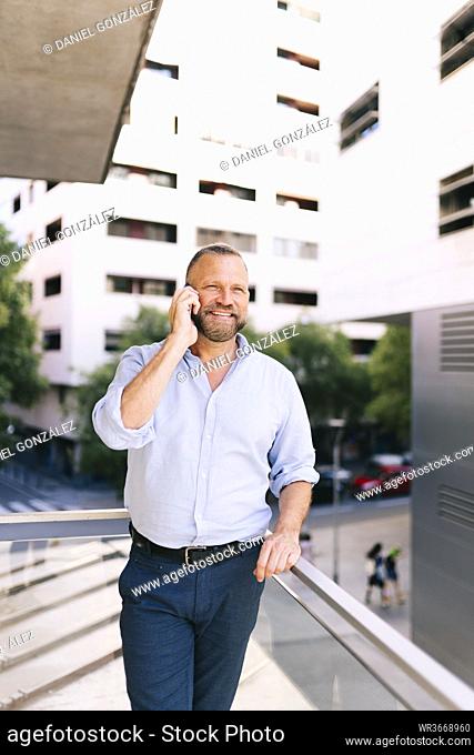 Businessman talking on mobile phone while standing in balcony of office