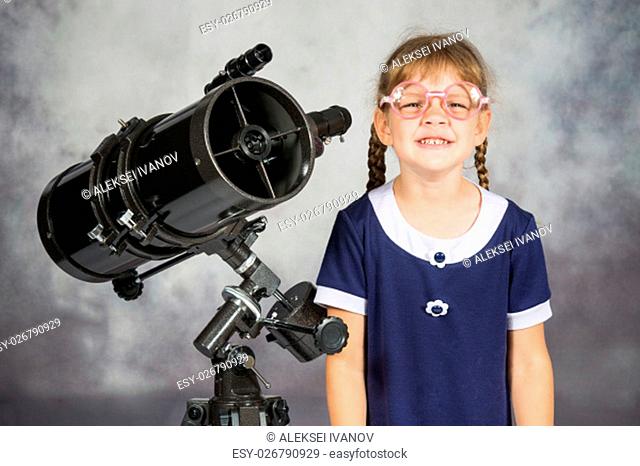 Girl bespectacled amateur astronomer funny smiling standing by telescope