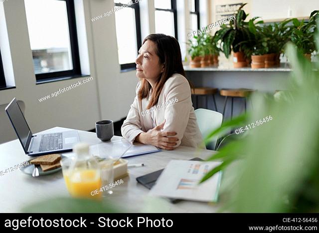 Empresaria pensativa trabajando en el portátil en la oficina