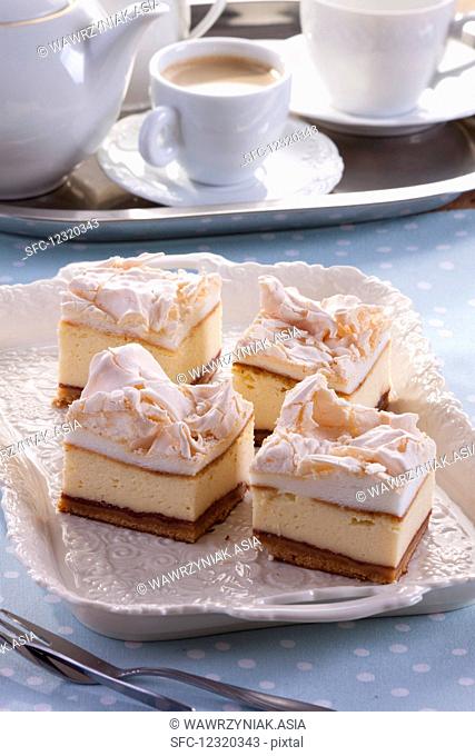Four pieces of cheesecake topped with meringue, served with coffee