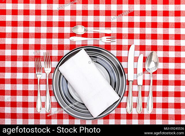 Old silver cutlery with plate on checkered tablecloth
