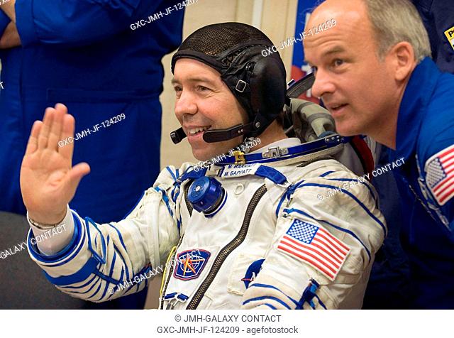 Expedition 19 Flight Engineer Michael R. Barratt, left, waves hello to family and colleagues with backup commander Jeffrey Williams in the suit up room of...