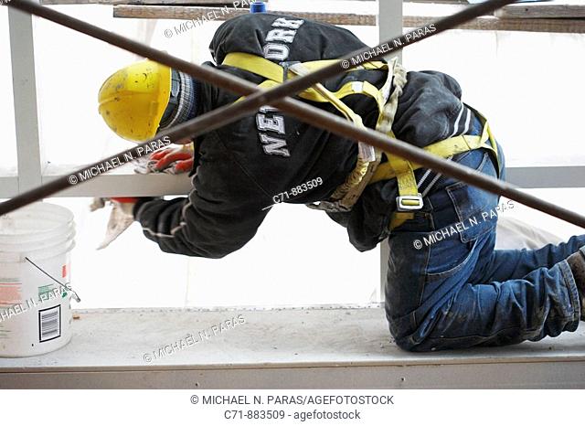Construction worker with safety harness belt cleaning