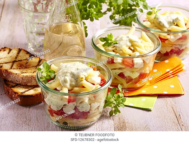 Italian layered salad with pasta, vegetables, yoghurt dressing and mozzarella in preserving jars