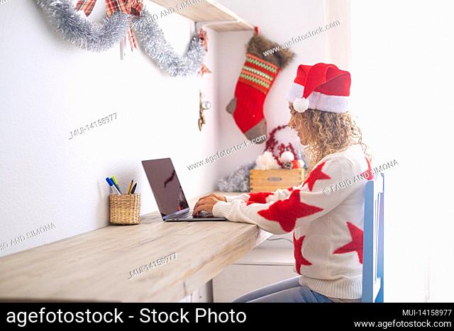 one single lady at home in christmas holidays using computer on the desktop workstation - white and bright apartment - new year december festivity - smart...