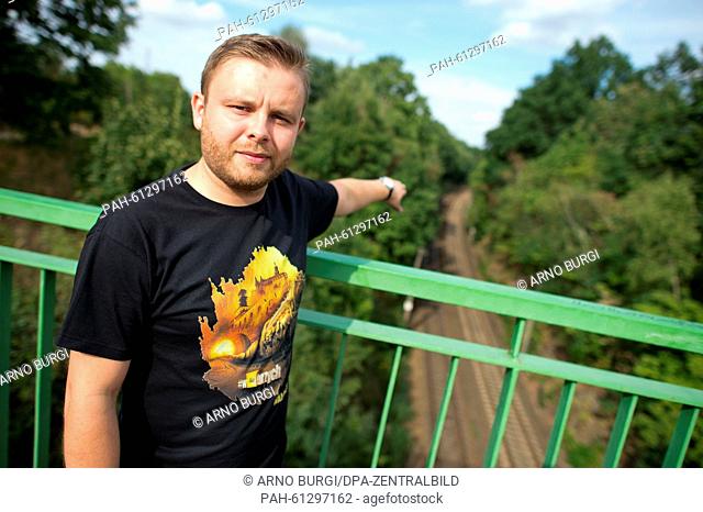 Tour guide Macciej Meissner, wearing a t-shirt which shows the depiction of a train and the writing 'Walbrzych' on it, points at the railway tracks on the train...