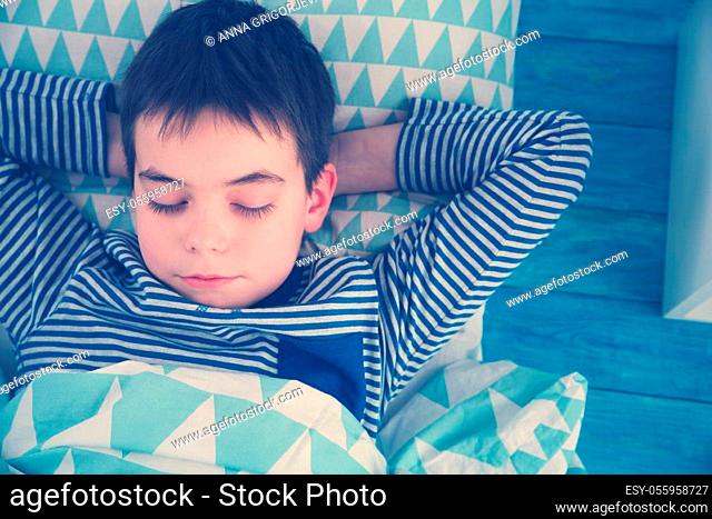 eight years old child sleeping in bed on pillow. Boy asleep on wooden background