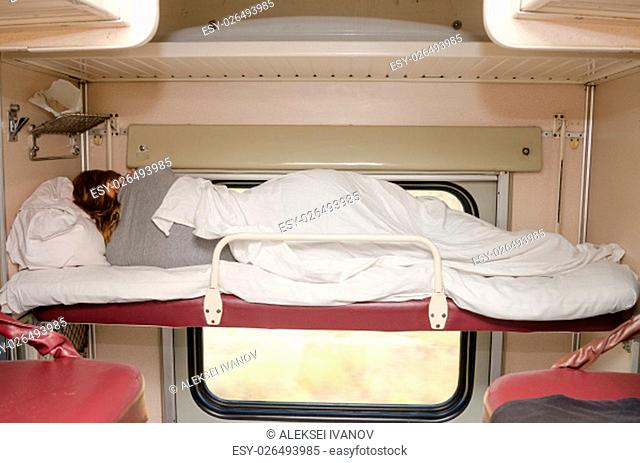 Passenger train sleeping on the top shelf of the side seats in the second-class carriage turned to the wall