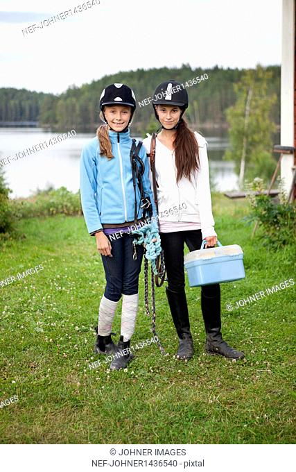 Two girls in jockey clothing standing on lawn