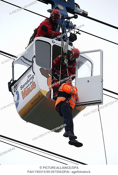 15 March 2019, North Rhine-Westphalia, Köln: Fire brigade height rescuers rope down a man from the gondola of the cable car over the Rhine during an exercise