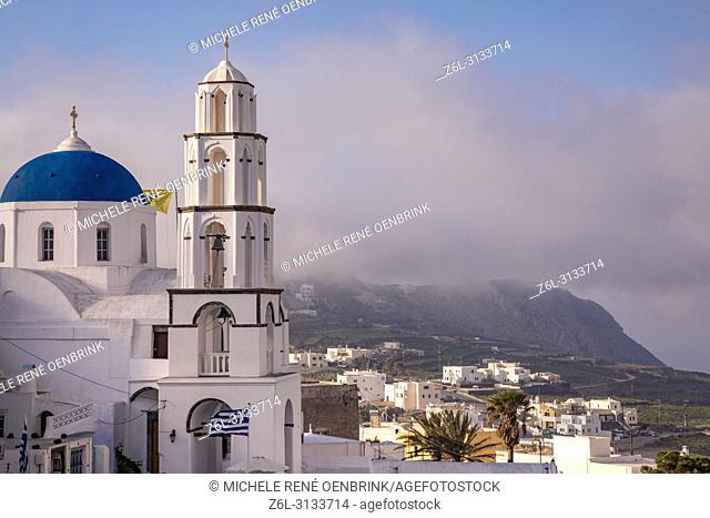 Traditional blue domed Greek Orthodox church with steeple and cross in Pyrgos, Santorini Greece