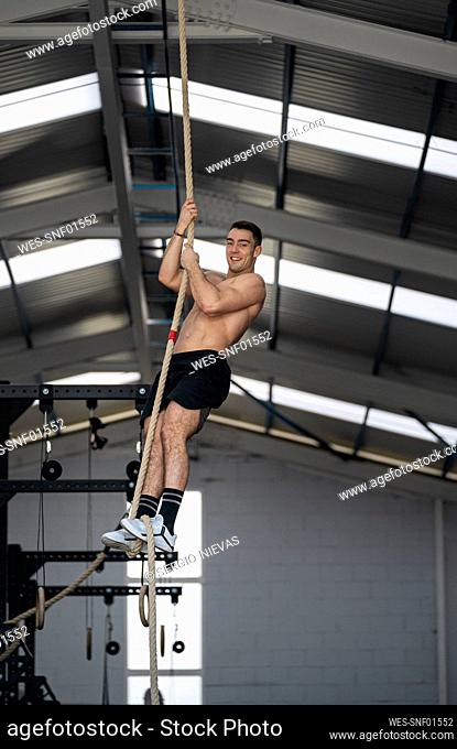 Smiling sportsman exercising with rope in gym