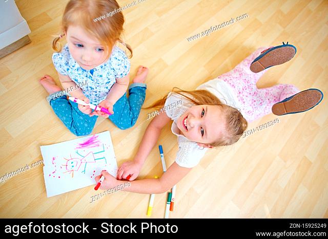 Zwei Kinder von oben beim Malen von einem Bild mit Filzstiften