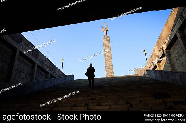13 November 2021, Armenia, Jerewan: A passerby stands at the top of the stairs of the Yerevan Cascade Complex above downtown Yerevan