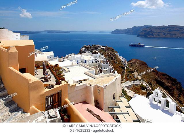 View above terraces overlooking caldera and ferry in the village of Oia in Santorini, Greece