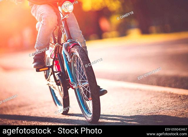 Child on a bicycle at asphalt road in early morning. Boy on bike in the city