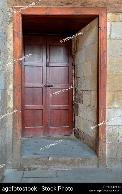 Recessed wooden aged engraved door and stone wall, Medieval Cairo, Egypt
