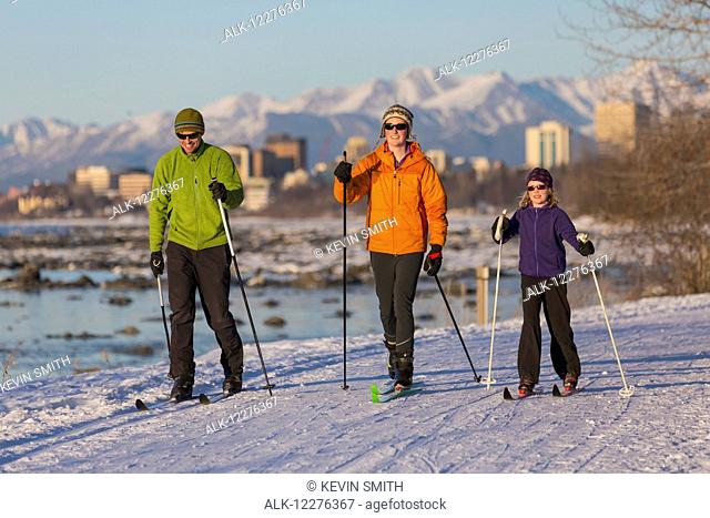 People cross country skiing on the Tony Knowles Coastal Trail near Earthquake Park with Anchorage skyline in the background, Cook Inlet, Southcentral Alaska