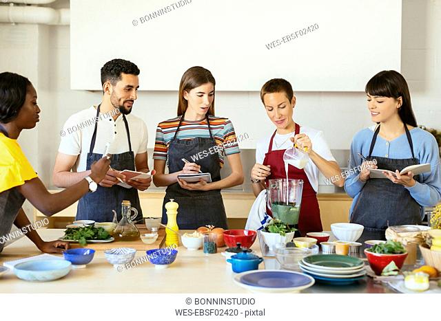 Friends and instructor in a cooking workshop preparing a smoothie
