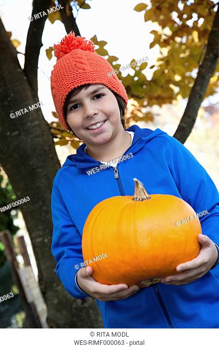Germany, Huglfing, Boy holding pumpkin, smiling, portrait
