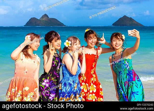 A group of Japanese students on vacation at Lanakai Beach with the Mokes Islands in the background: Oahu, Hawaii, United States of America
