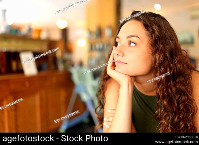 Distracted and pensive woman looking away in a restaurant