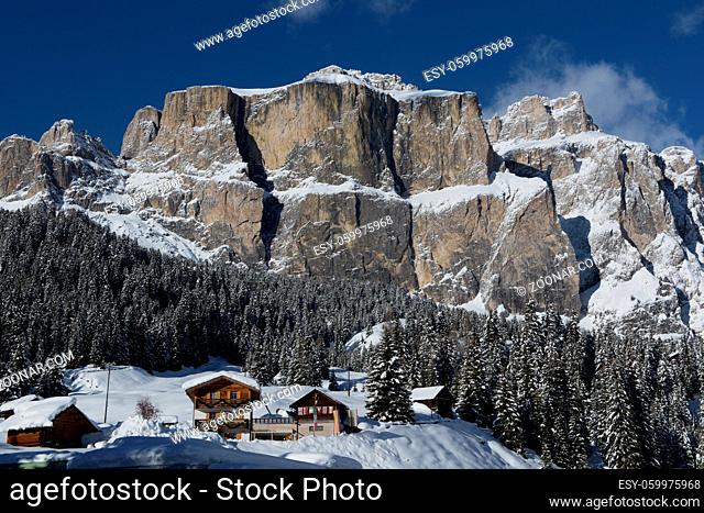 Chalet and trees under the snow in the idyllic landscape of the dolomiti in Val di Fassa