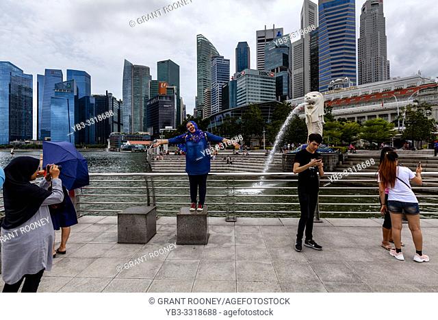Tourists Posing For Photos In Front Of The Merlion Statue and Singapore Skyline, Singapore, South East Asia