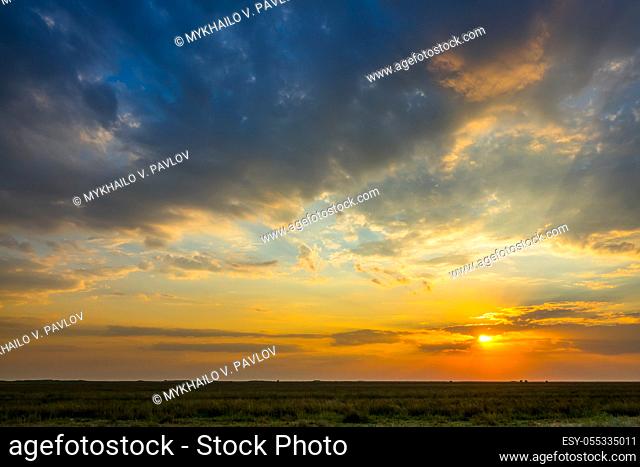 Summer steppe. Colorful sunset with illuminated clouds