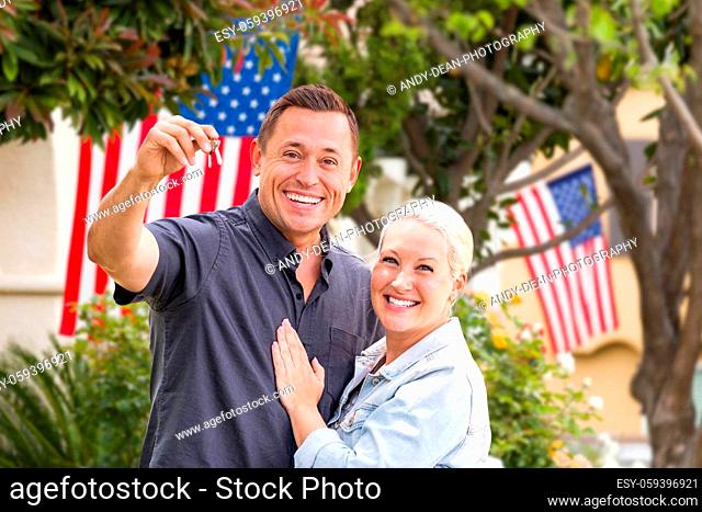 Happy Couple With New House Keys In Front of Houses with American Flags