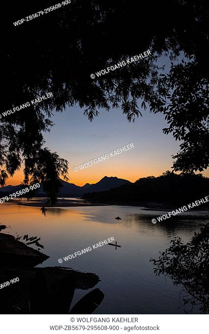View of the Mekong River with a fisherman in a boat after sunset near the UNESCO world heritage town of Luang Prabang in Central Laos